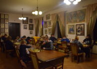 Widok na całą salę. Przy ustawionych równolegle do siebie stołach siedzą zawodnicy i grają w szachy.