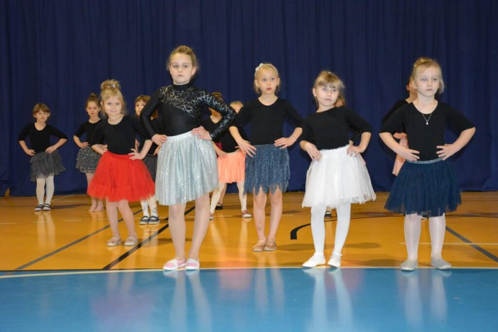 Na zdjęciu widoczna grupa dziewczynek w kolorowych sukienkach i czarnych bluzkach.