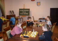 Przy rzędzie stołów zawodnicy grają w szachy.