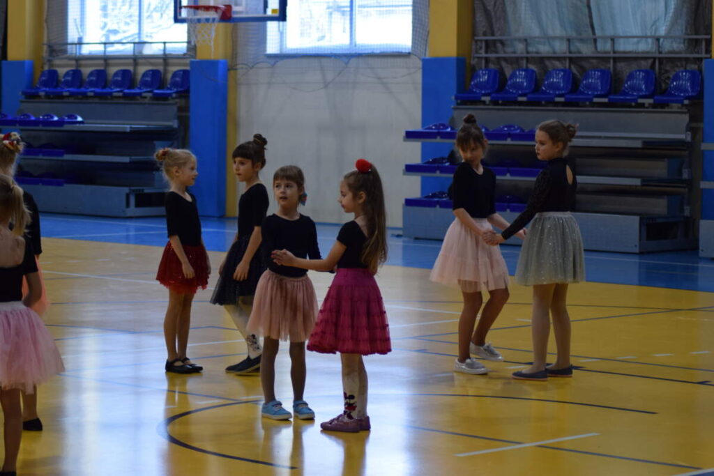 Na zdjęciu widoczna grupa dziewczynek w kolorowych sukienkach i czarnych bluzkach.