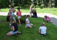 Dzieci siedzą na trawie i robią zdjęcia.